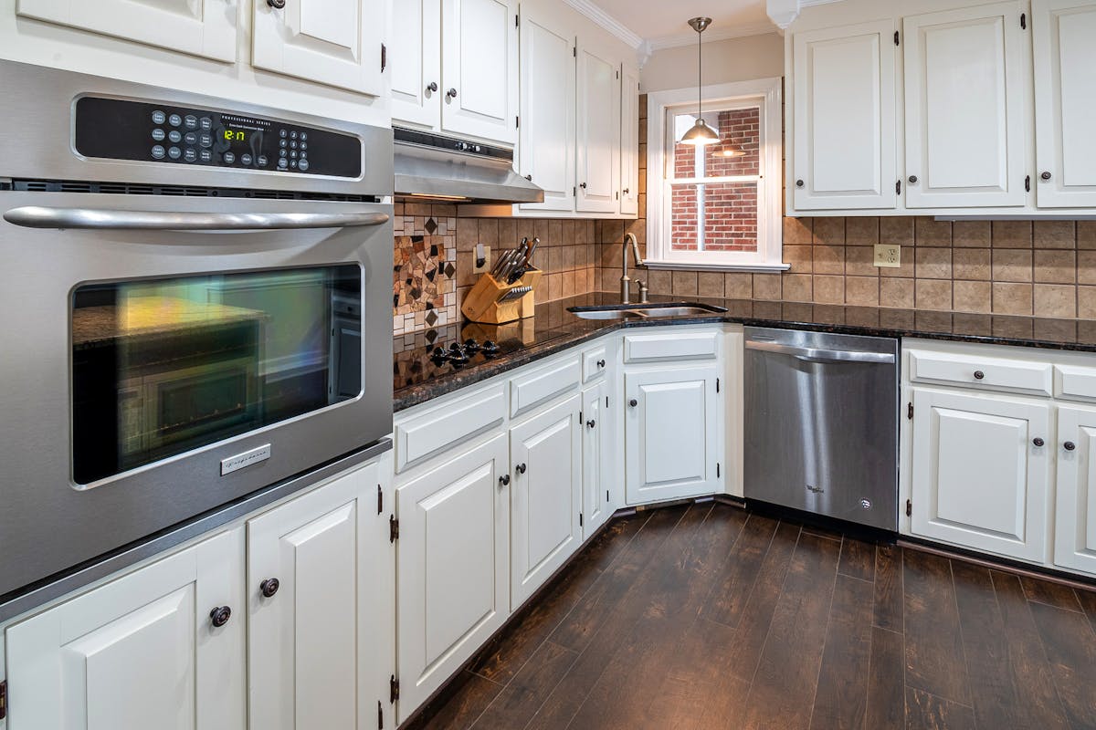Custom kitchen cabinets Brisbane installation showing white shaker-style cabinetry with stone benchtops